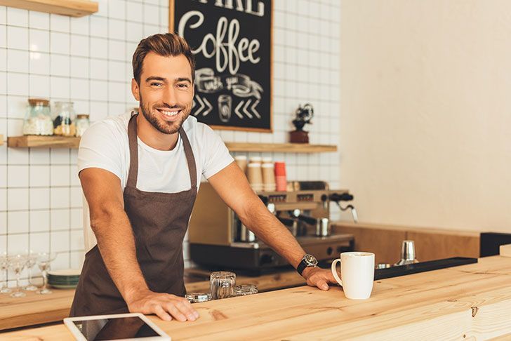 smiling coffee shop owner/barista behind counter