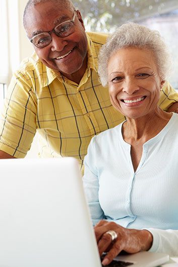 smiling senior black couple using laptop